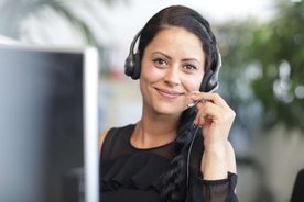 Eine junge Mitarbeiterin hat Spaß im Callcenter.